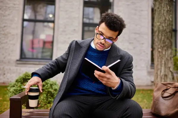 Messieurs absorbés en lisant un livre, sirotant un café par une journée ensoleillée dans un parc serein. — Photo de stock