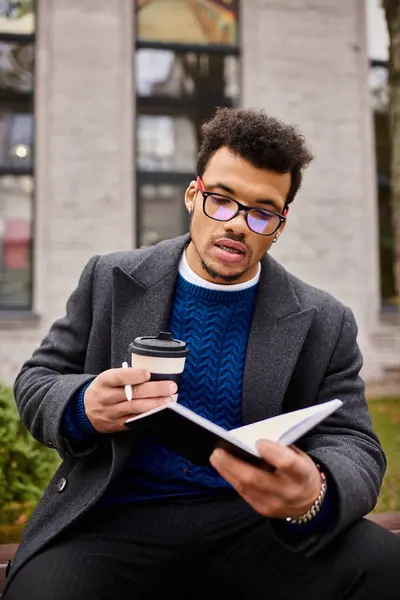 Handsome man catches up on reading while lounging outside with a warm cup of coffee. — Stock Photo