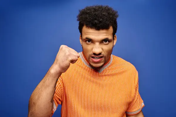 A handsome man displays passion and strength with a determined expression and raised fist. — Stock Photo