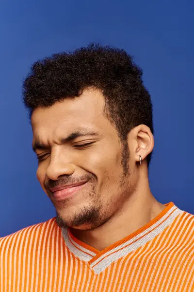A charming man displays a joyful expression while wearing a striped orange shirt. — Stock Photo