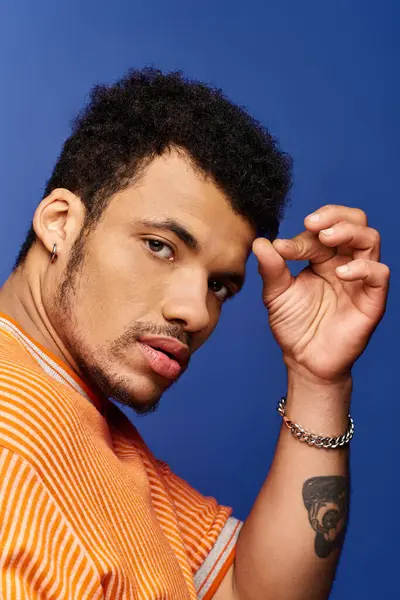 A handsome man showcases a thoughtful expression while playfully adjusting his hair. — Stock Photo