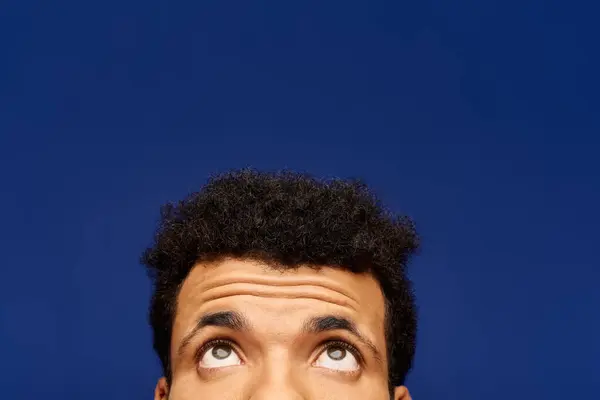 A handsome man looks thoughtfully upwards, his expression hinting at curiosity and wonder. — Stock Photo