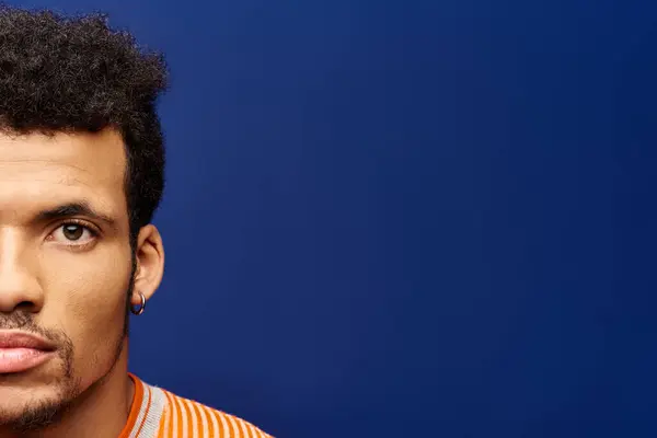 A confident man showcases his unique style while posing with a striking blue background. — Stock Photo