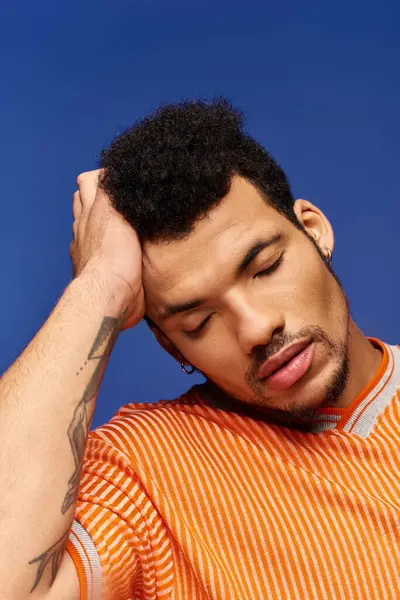A stylish man relaxes with his hand on his head, set against a vibrant backdrop. — Stock Photo