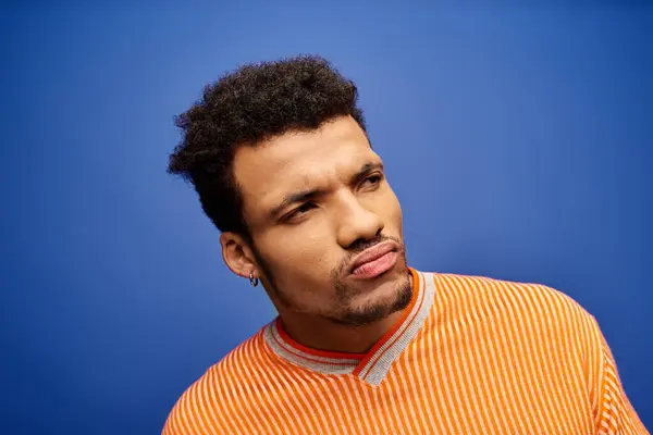 Stylish man with curly hair showcases fashion and personality in a bright blue background. — Stock Photo