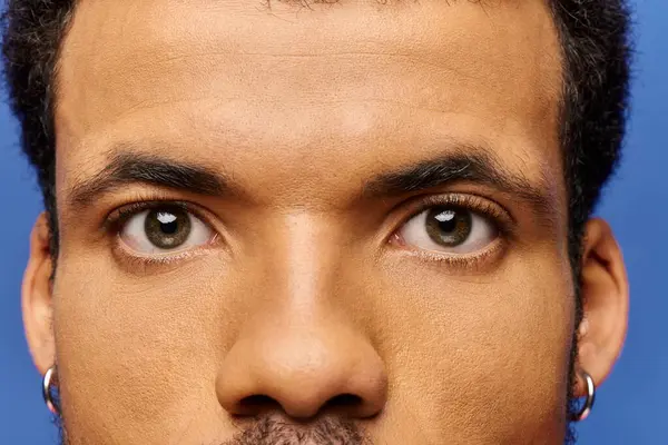 A handsome man gazes intensely, showcasing captivating eyes and a unique earring. — Stock Photo