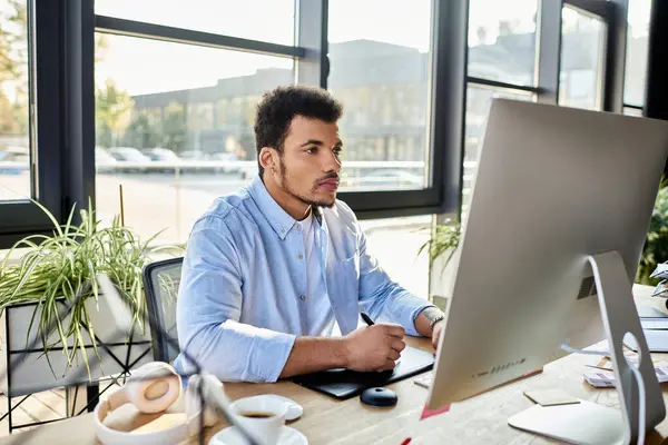 A focused man works diligently at his desk, surrounded by greenery and bright sunlight. — Stock Photo