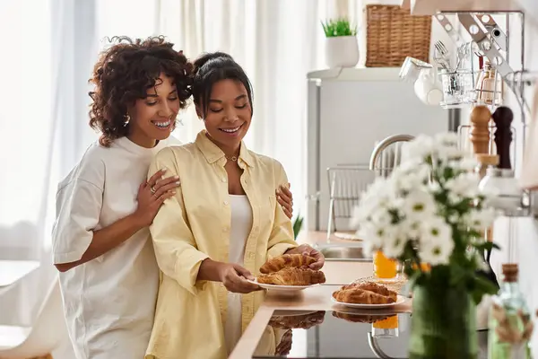 Two joyful women share a delightful breakfast moment in their modern kitchen. — Stock Photo