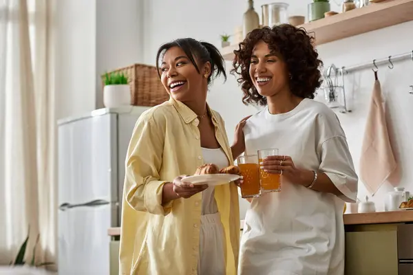 Deux jeunes femmes dégustent un petit déjeuner animé ensemble rempli de rire dans une cuisine élégante. — Photo de stock