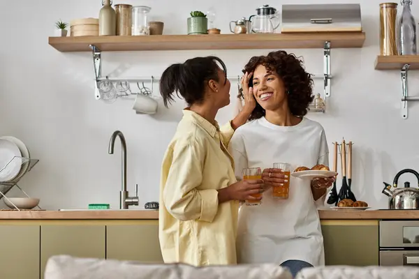 Two young women enjoy a cheerful breakfast together in their stylish apartment, embracing love. — Stock Photo