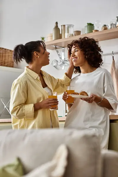 Two young women share laughter and love over breakfast in their bright apartment. — Stock Photo