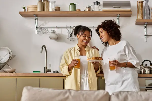 Two young women share laughter and love over breakfast in their sleek apartment. — Stock Photo