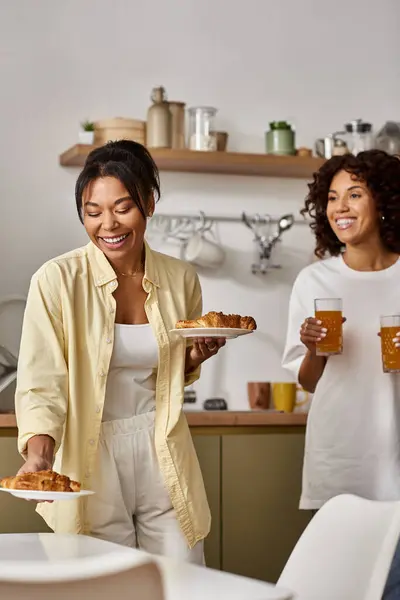 Due giovani donne gustare la colazione insieme in un elegante appartamento pieno di amore e risate. — Foto stock