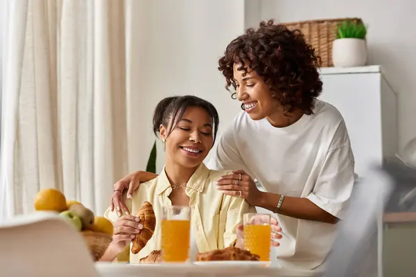 Zwei junge afroamerikanische Frauen genießen ein fröhliches gemeinsames Frühstück, lachen und teilen. — Stockfoto