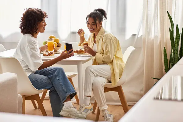 A young African American couple enjoys breakfast in their modern apartment while sharing smiles. — Stock Photo