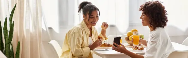 Deux jeunes femmes prennent le petit déjeuner ensemble, célébrant l'amour et la connexion dans un espace confortable, bannière — Photo de stock