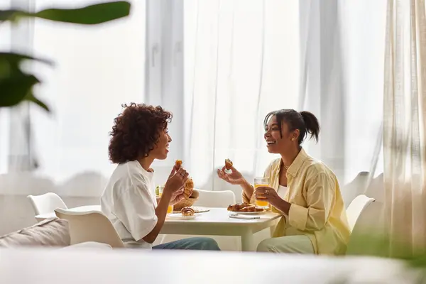 Two young African American women share a joyful breakfast together in a bright apartment. — Stock Photo