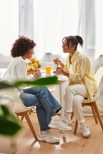 Two women share joyful moments over breakfast while surrounded by sunshine in a chic apartment. — Stock Photo