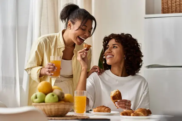 A young lesbian couple shares a joyful breakfast moment in their stylish apartment filled with love. — Stock Photo