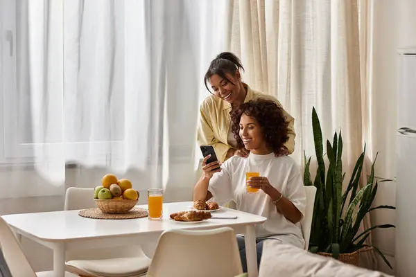 Un jeune couple joyeux prend le petit déjeuner ensemble, partageant sourires et rires dans leur appartement. — Photo de stock