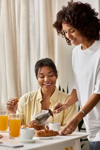 A young lesbian couple shares joy while having breakfast together in a bright modern space. — Stock Photo