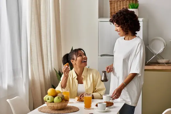 Two young African American women enjoy a cheerful breakfast together in their cozy home. — Stock Photo