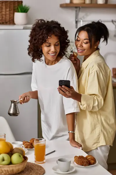 Due giovani donne condividono sorrisi e risate durante la colazione nel loro elegante appartamento. — Foto stock