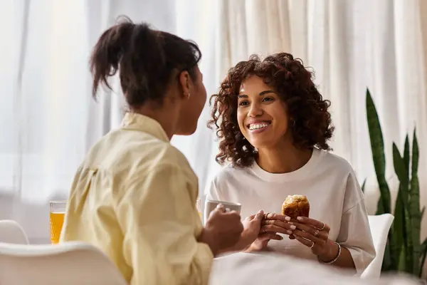 A young lesbian couple enjoys breakfast together, smiling and connecting in their cozy apartment. — Stock Photo