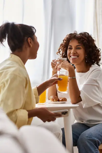 Two young women enjoy breakfast together in their stylish apartment, sharing laughter and love. — Stock Photo