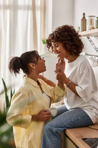 Two young women share a tender moment in their stylish living space, embracing love and joy. — Stock Photo