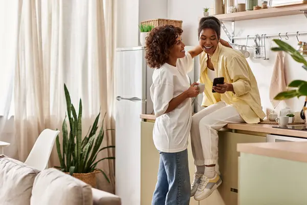Two women share laughter and joy as they connect in their modern apartment, embracing love. — Stock Photo