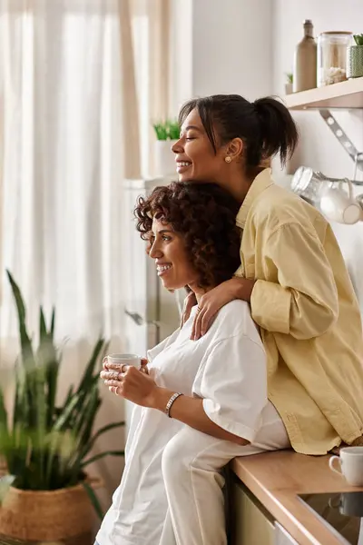 Two women share laughter and warmth while relaxing in their modern living space. — Stock Photo