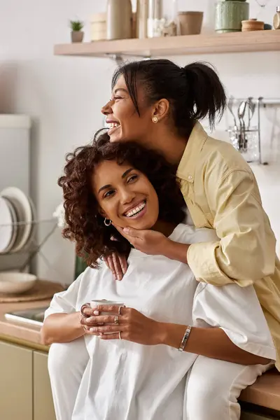 Two happy women share a loving moment in their chic kitchen, showcasing their bond. — Stock Photo