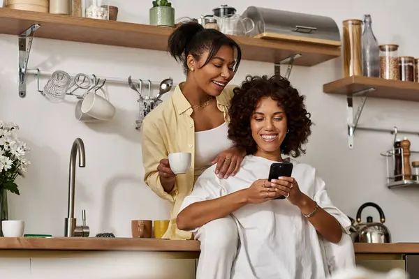 Two young women share laughter as they enjoy their time together in a modern kitchen. — Stock Photo
