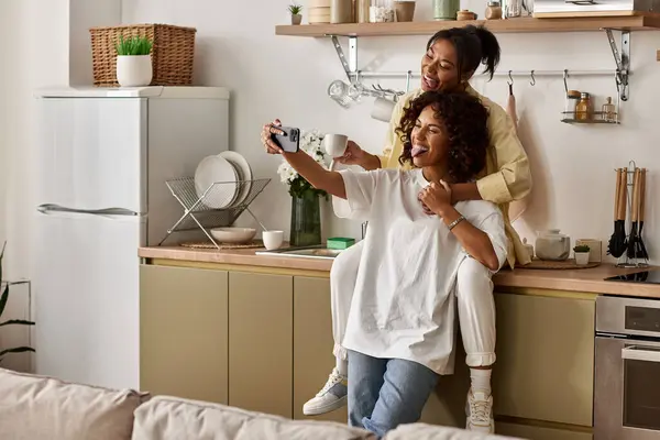 Two young women enjoy each others company while taking a selfie in their cozy apartment. — Stock Photo
