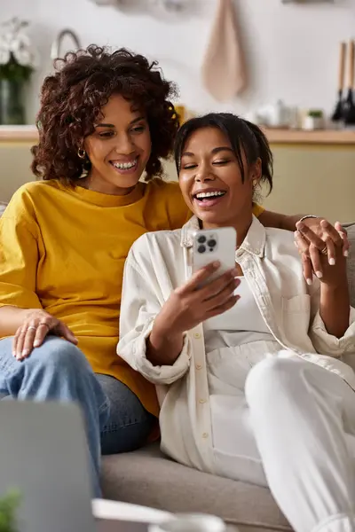Two young women share laughter while enjoying their time together in a stylish modern space. — Stock Photo