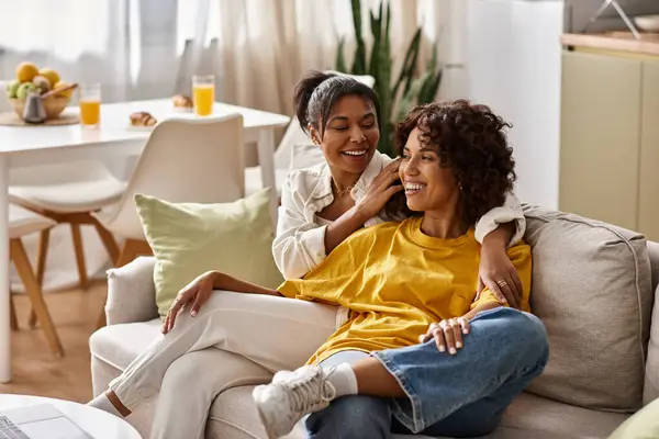 Two young women share laughter and affection in their bright modern apartment, embodying love. — Stock Photo