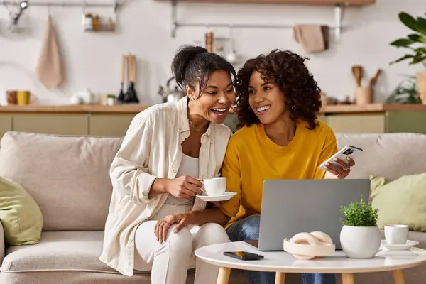 Two young women share joyful moments while working remotely from their stylish apartment. — Stock Photo