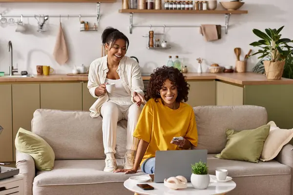 Deux jeunes femmes partagent un moment de joie en regardant un film dans leur appartement élégant. — Photo de stock