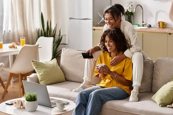 Two young women share joyful moments while watching movie in their contemporary apartment setting. — Stock Photo
