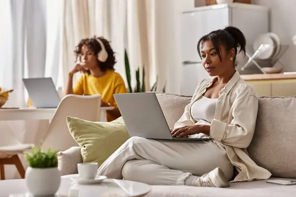 Two young women are focused on their laptops in a modern apartment, enjoying their workday together. — Stock Photo
