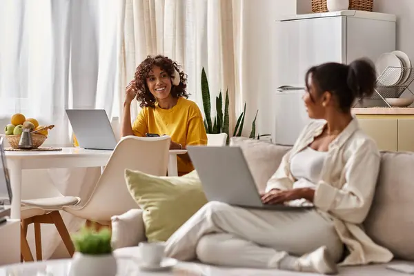 Deux jeunes femmes afro-américaines collaborent à des tâches professionnelles tout en partageant des moments confortables à la maison. — Photo de stock