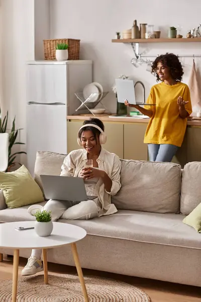 Dos mujeres jóvenes trabajan lado a lado en su elegante apartamento, abrazando la vida remota. - foto de stock