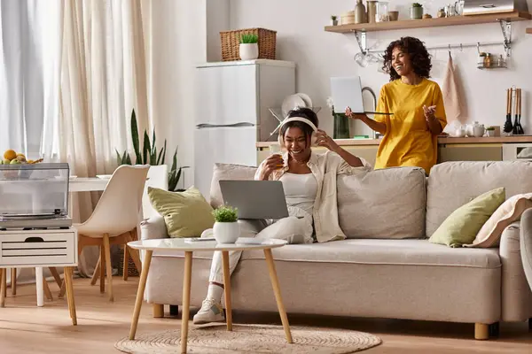 Two young women share a joyful moment while working from home in their stylish living space. — Stock Photo