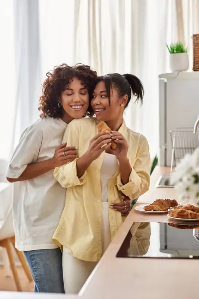 Two young women enjoy a joyful breakfast together in their stylish kitchen. — Stock Photo