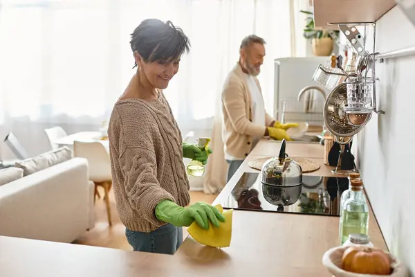 Pareja comparte momentos alegres mientras limpian y organizan su cocina luminosa juntos - foto de stock