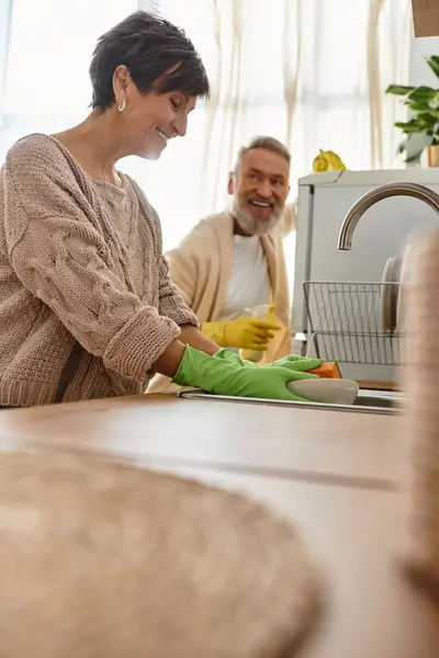 A mature couple moments together in their kitchen, sharing smiles as they cook and enjoy life. — Stock Photo