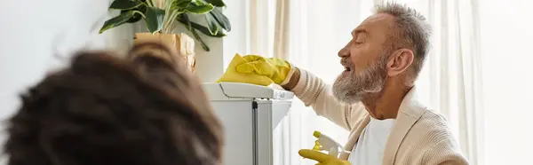 Mature couple engages joyfully in cleaning their refrigerator while smiling at each other warmly. — Stock Photo