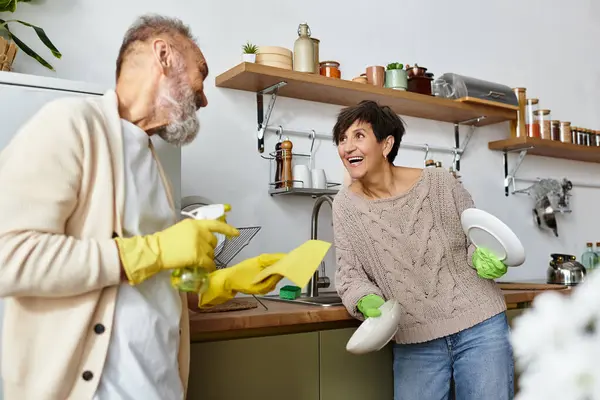Uma mulher e um homem compartilham sorrisos enquanto arrumam sua cozinha, criando uma atmosfera alegre juntos.. — Fotografia de Stock