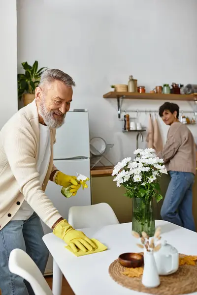 Senior couple shares a joyful moment as they clean and organize their cozy kitchen space. — Stock Photo
